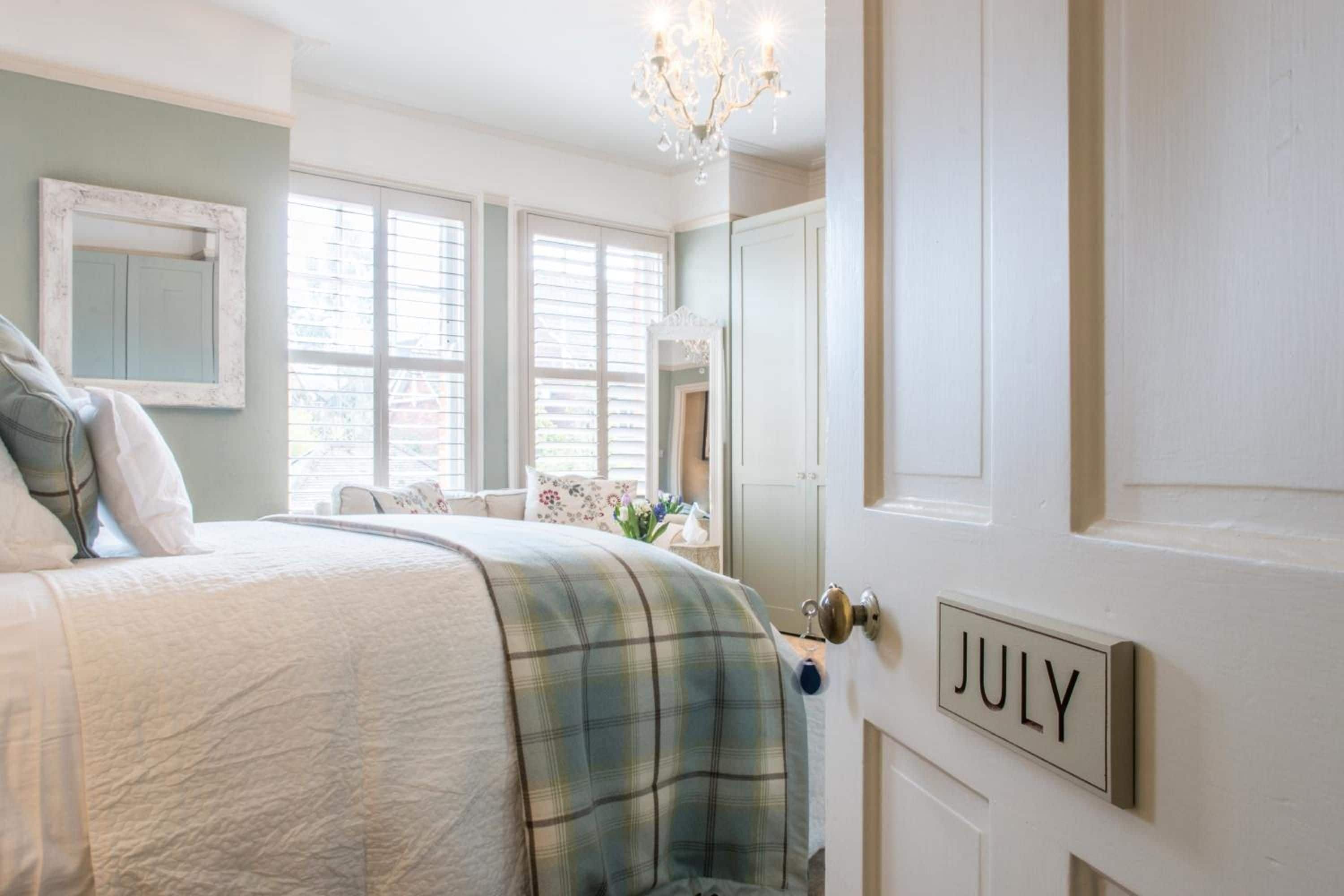 Une chambre à coucher comprenant un lit, une commode, un miroir et une porte avec une plaque nominative.
