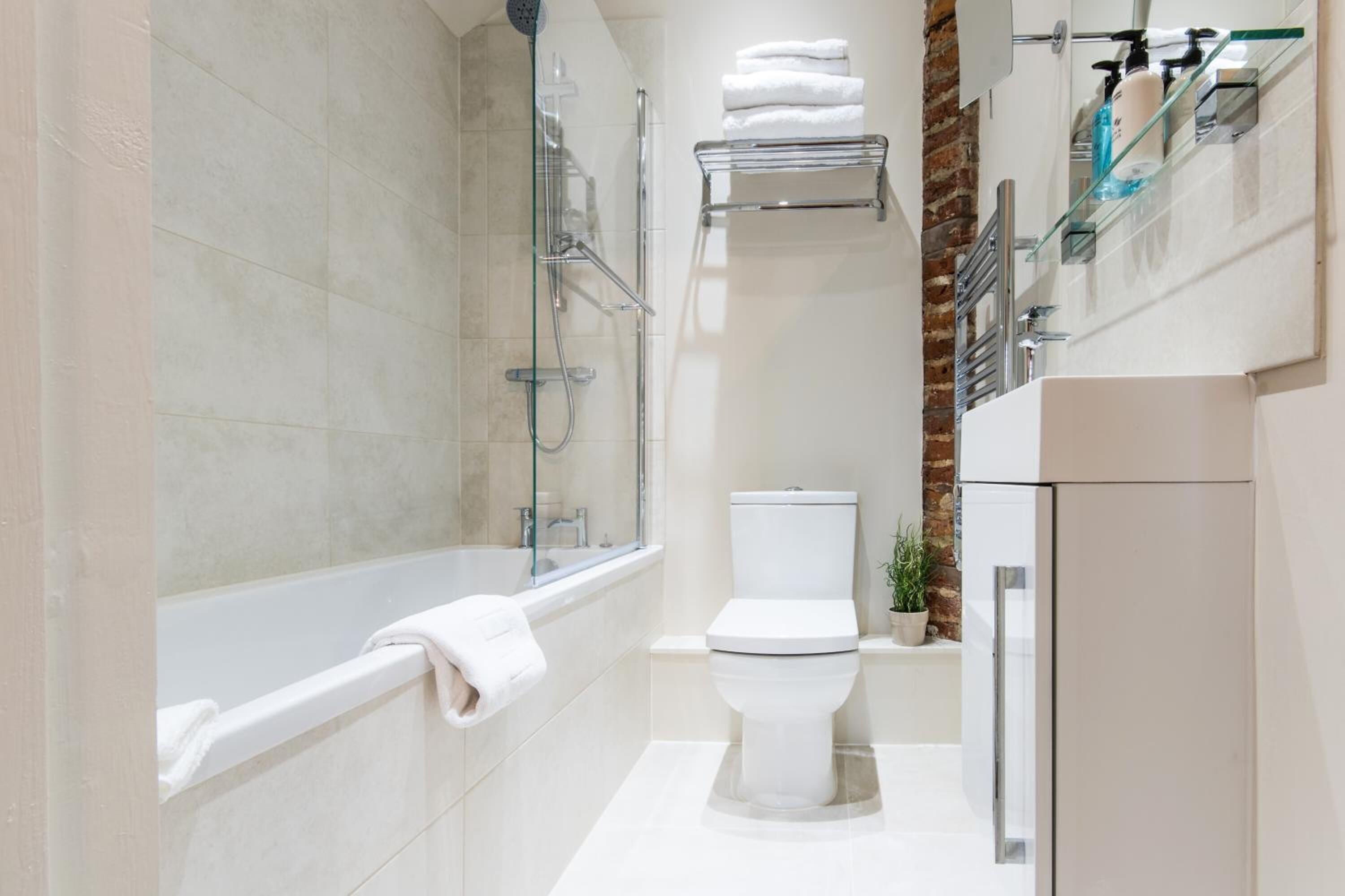 A modern bathroom with a bathtub, toilet, and glass shower enclosure.