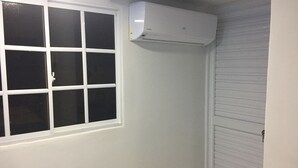 A room with a window, an air conditioning unit mounted on the wall, and a closed door. - Bluehouse backpackers club, hostel excelente ubicación buen precio San Andrés I (San Andrés)