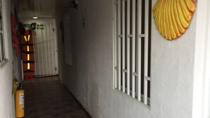 A hallway with a tiled floor, a white door with barred windows, and a yellow fire extinguisher on the wall. - Bluehouse backpackers club, hostel excelente ubicación buen precio San Andrés I (San Andrés)