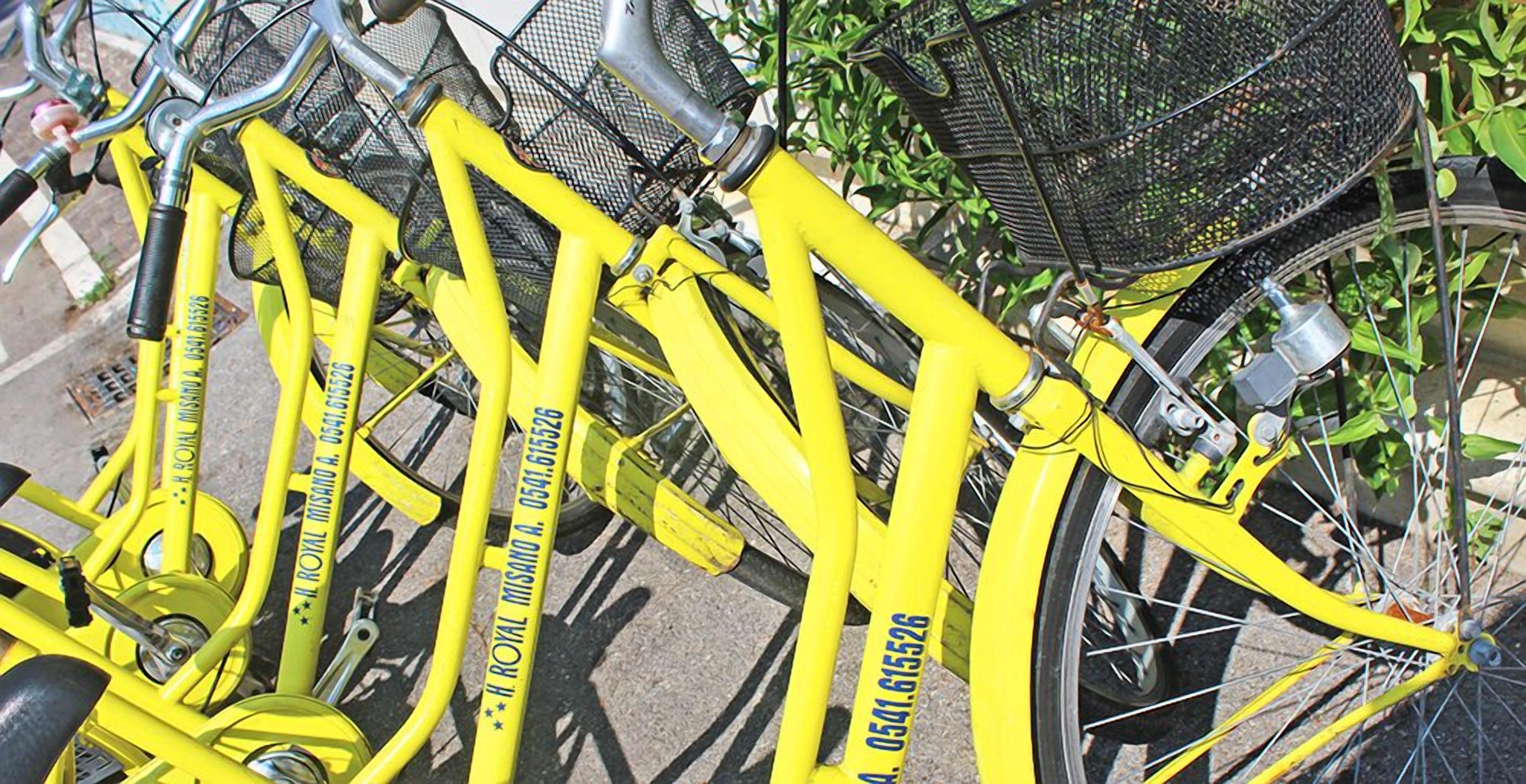 Una bicicleta amarilla con una cesta y una botella de agua sujeta al cuadro.