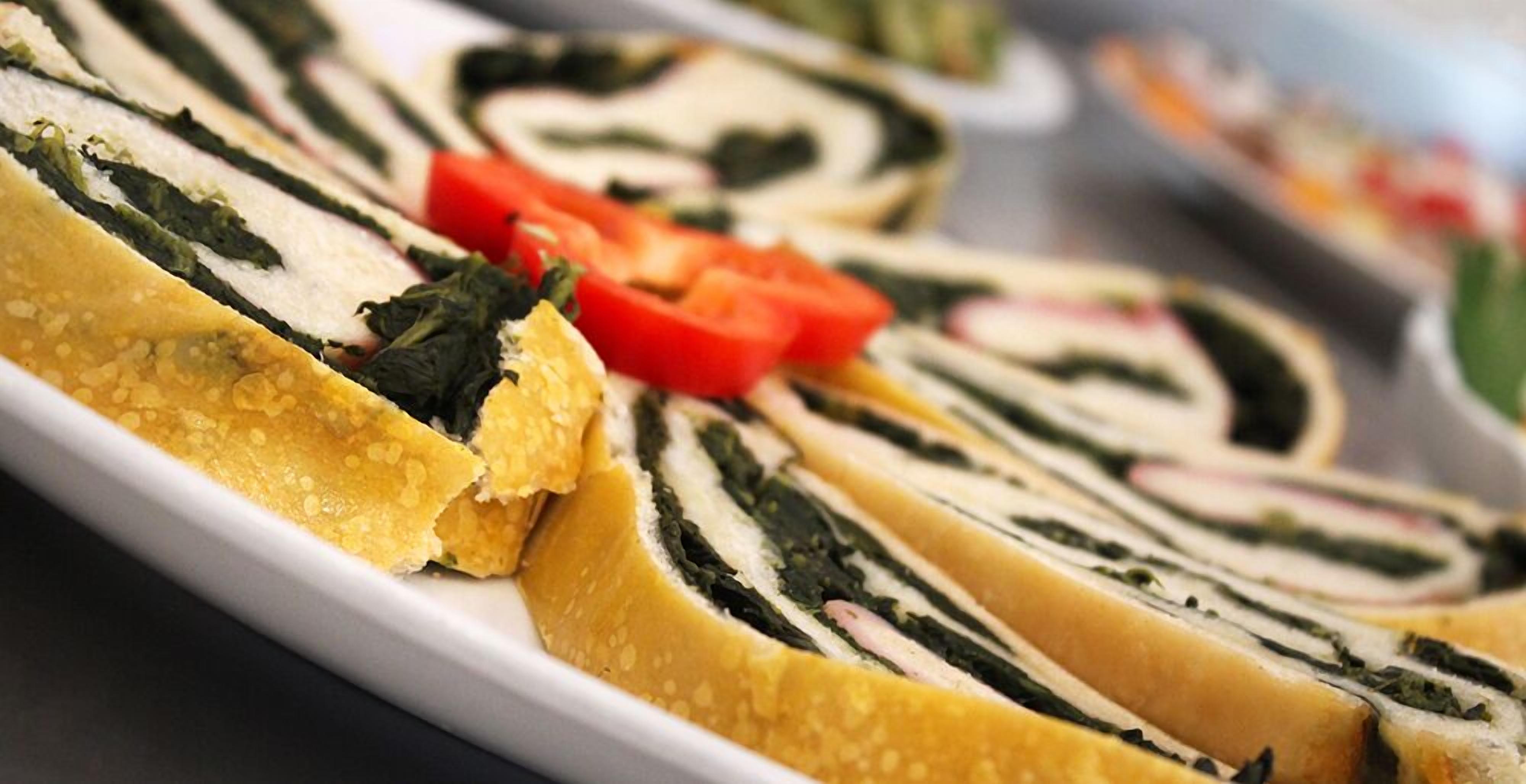 A plate of sushi rolls with seaweed and tomato slices.