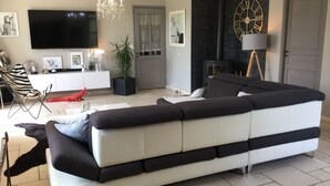 A modern living room with a large sectional sofa, a flat-screen TV, a chandelier, and a fireplace. - Vacation rental house with pool MOURIES LS1-343 (Mouriès)