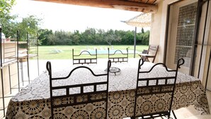 An outdoor patio with a table and chairs, a view of a swimming pool, and a covered area with a pergola. - Vacation rental house with pool MOURIES LS1-343 (Mouriès)