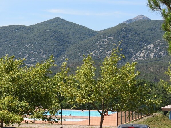 A pool area with a view of mountains, surrounded by trees.