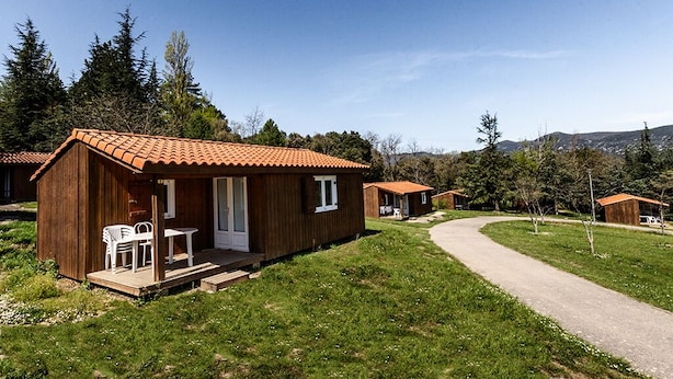 Eine Reihe Holzhütten mit Ziegeldächern, jede mit einer Veranda und Sitzgelegenheiten im Freien.