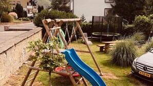 Um parquinho com escorrega e balanços em área residencial.