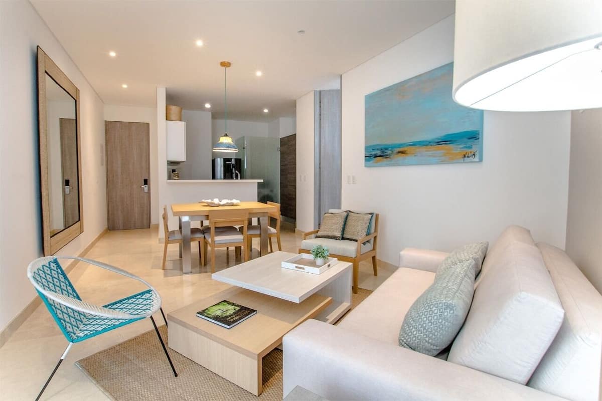 A modern living room with a sofa, a coffee table, and a dining area with a table and chairs.
