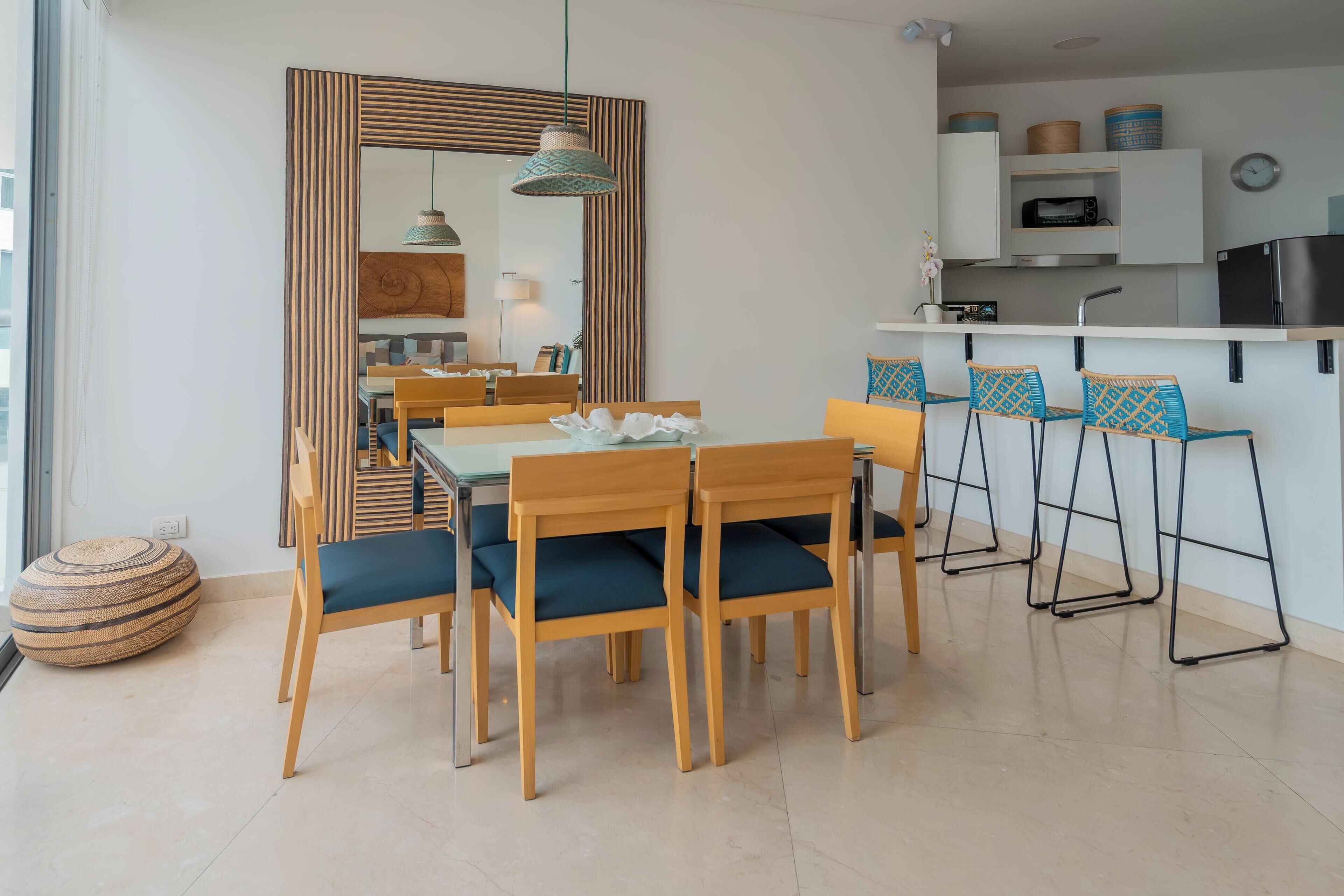 A modern kitchen with white cabinets, a black refrigerator, and a dining area with wooden chairs and a table.