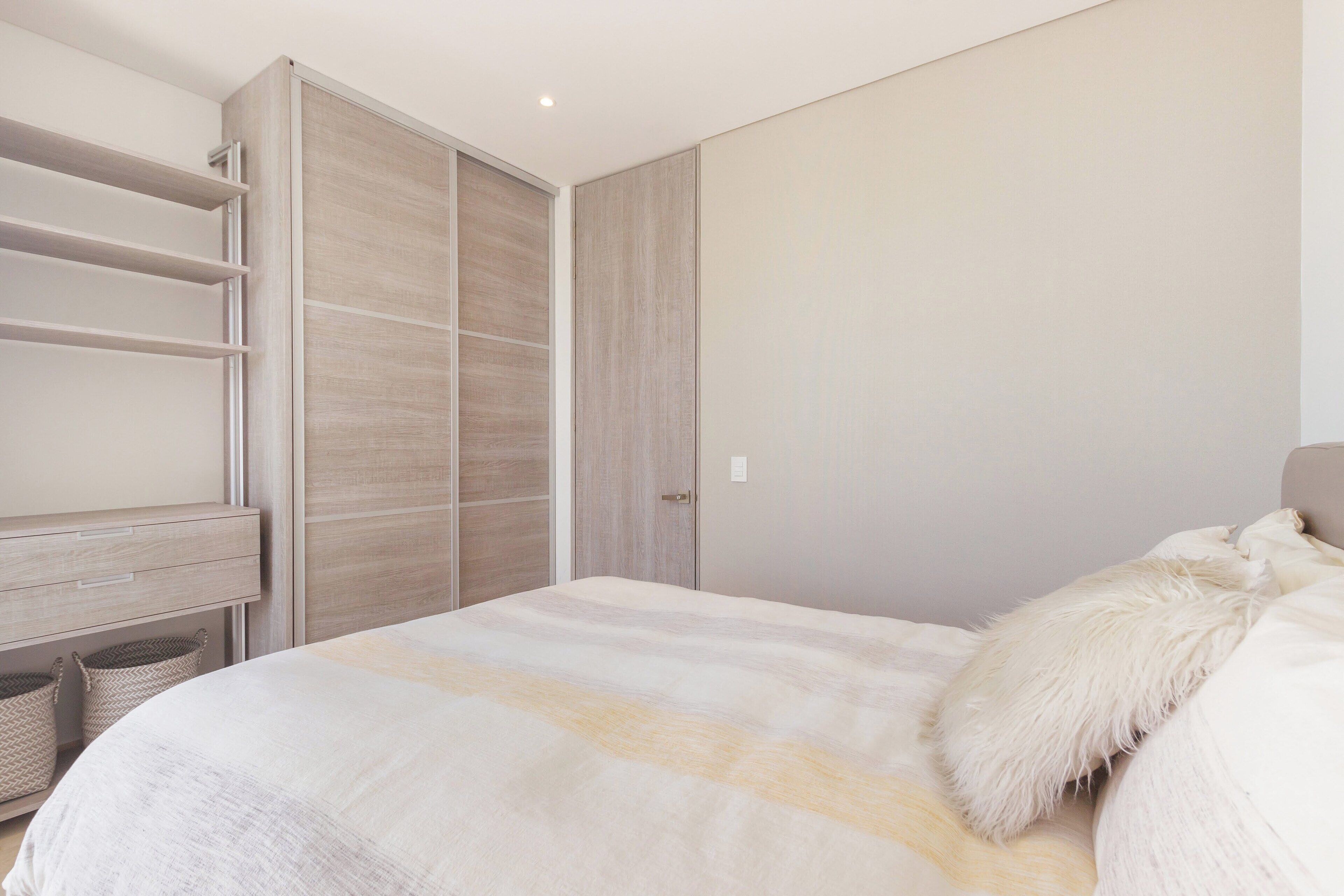 Um quarto com uma cama, um guarda-roupa e uma mesa de cabeceira.