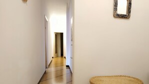 A hallway with a tiled floor, a wicker chair, and a mirror on the wall. - Holiday Apartment in Santa Margherita (Santa Margherita Ligure)