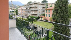 A balcony with a view of a residential area, including multi-story buildings and a tall tree. - Holiday Apartment in Santa Margherita (Santa Margherita Ligure)