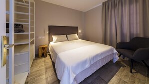 A bedroom with a bed, a chair, a wardrobe, and a nightstand. - Costa Adeje Garden (Adeje)