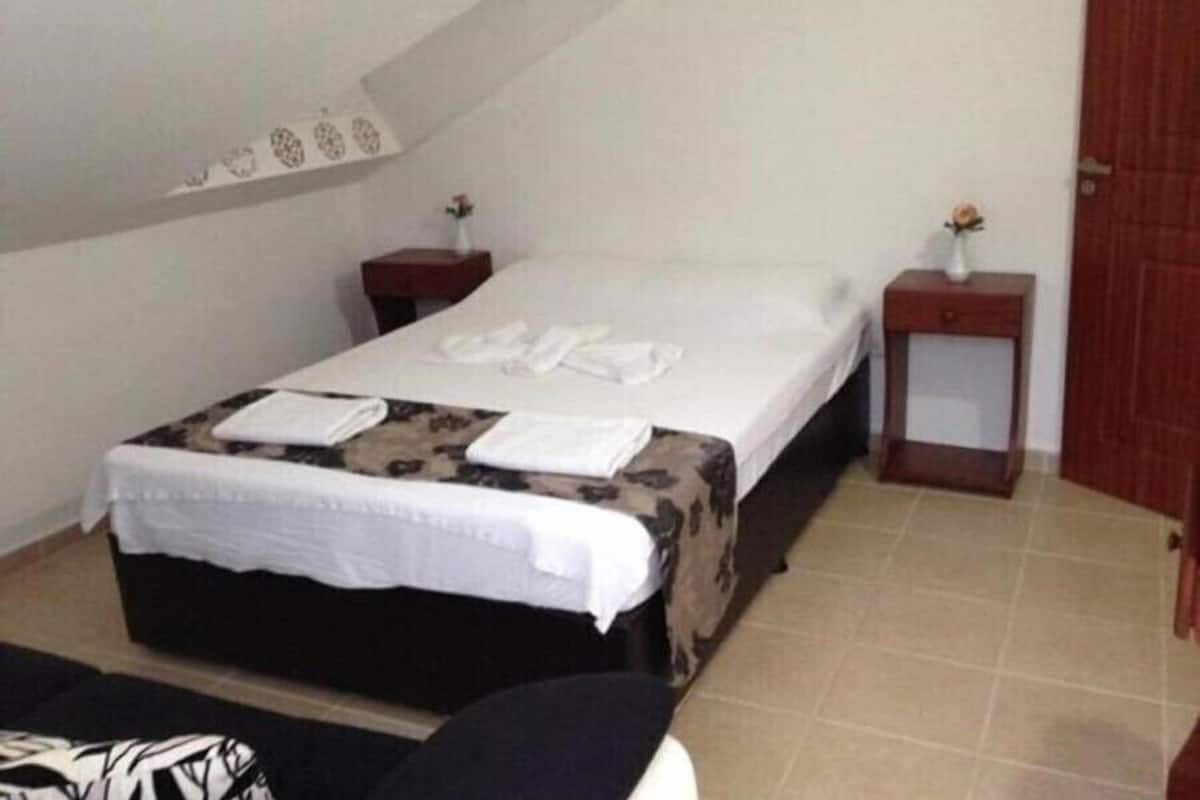 A small, neatly arranged bedroom with a bed, bedside tables, and a nightstand.