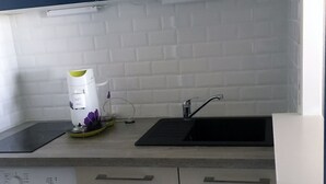 A compact kitchen with a washing machine, a sink, and a compact refrigerator. - 47m2 duplex apartment - type 2 with terrace (Frejus)