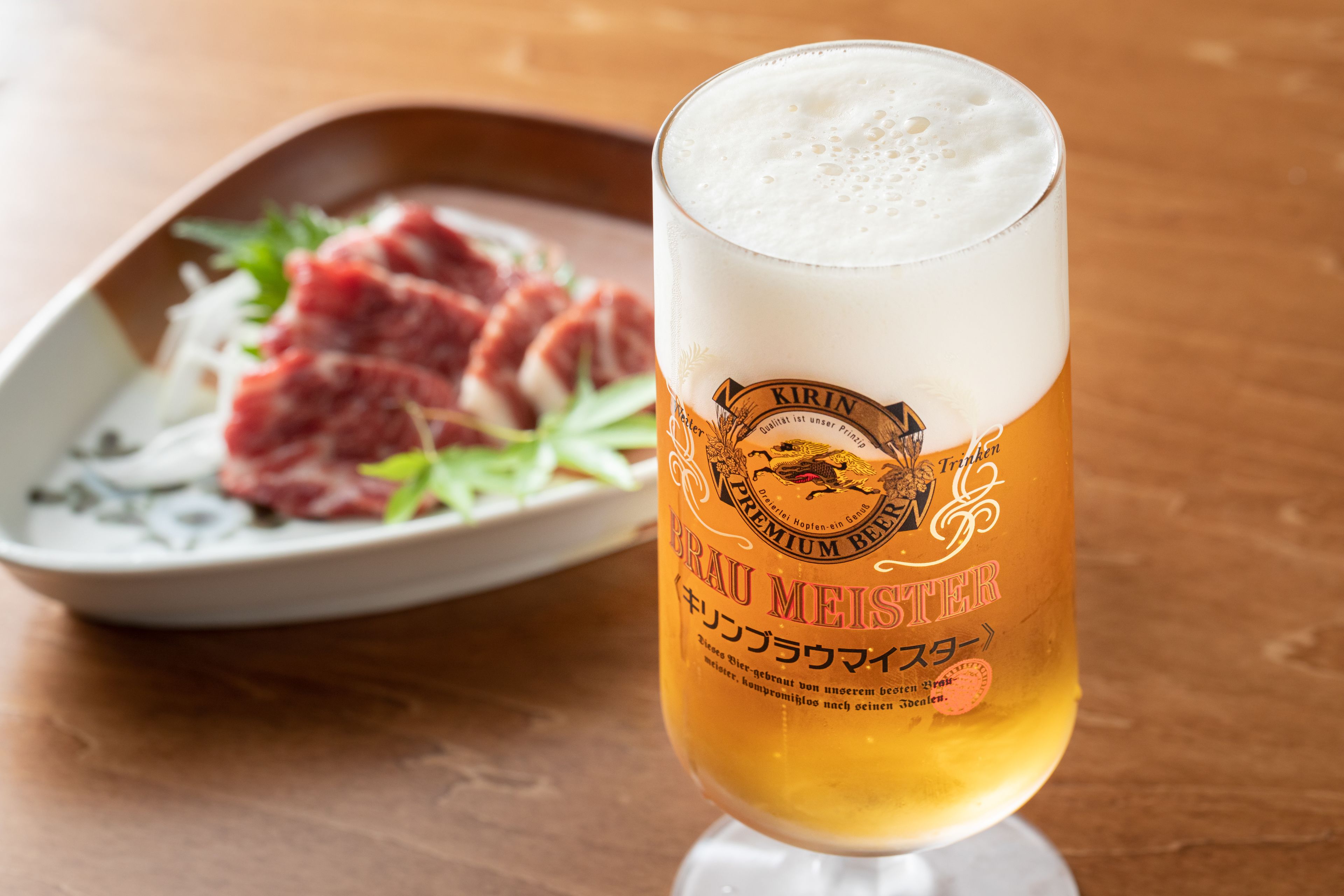 A glass of beer with a label, placed on a wooden table.
