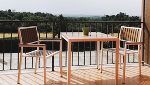 Ein Balkon mit zwei Holzstühlen und einem Tisch, der auf eine malerische Landschaft blickt.