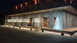 Ein modernes Hotel mit einer Betonfassade, mehreren Balkonen und einer markanten, spiralförmigen Lichtinstallation am Eingang.