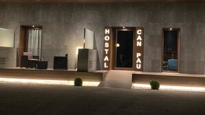 Ein moderner Hotelzugang mit minimalistischem Design, mit einer Rezeption, einer Sitzecke und einem deutlich ausgeschilderten Schild mit der Aufschrift "HOSTAL CAN PAU".