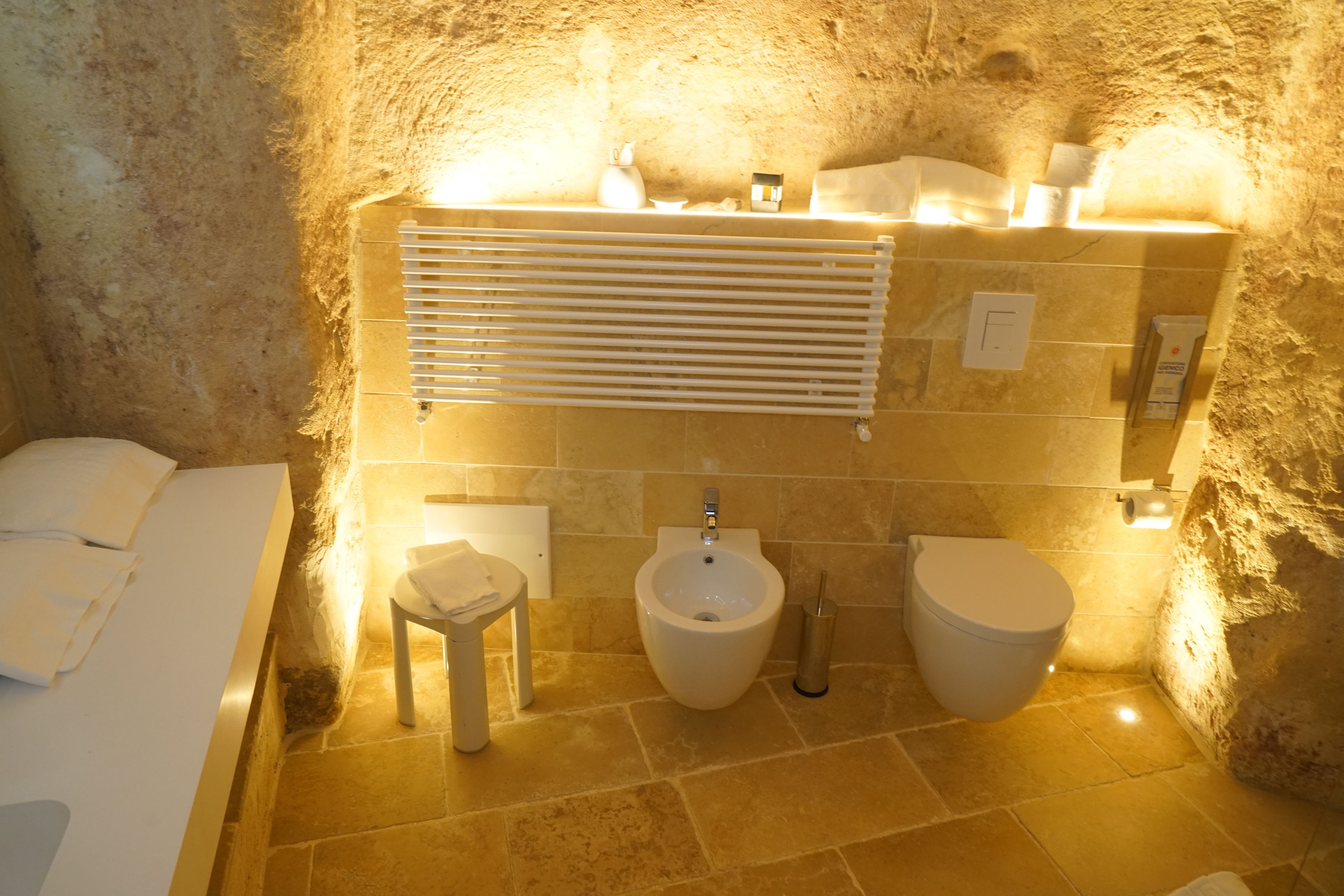 A bathroom with a bidet, toilet, and a small stool.
