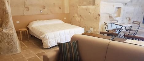 A cozy room with a bed, a sofa, and a dining area with chairs and a table.