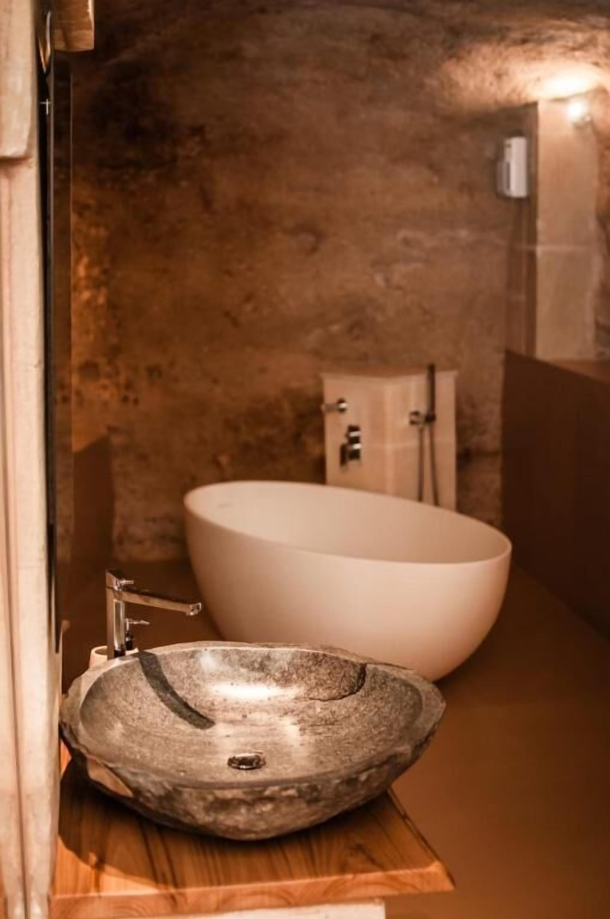 Un baño con una bañera ovalada grande y un lavamanos de piedra.