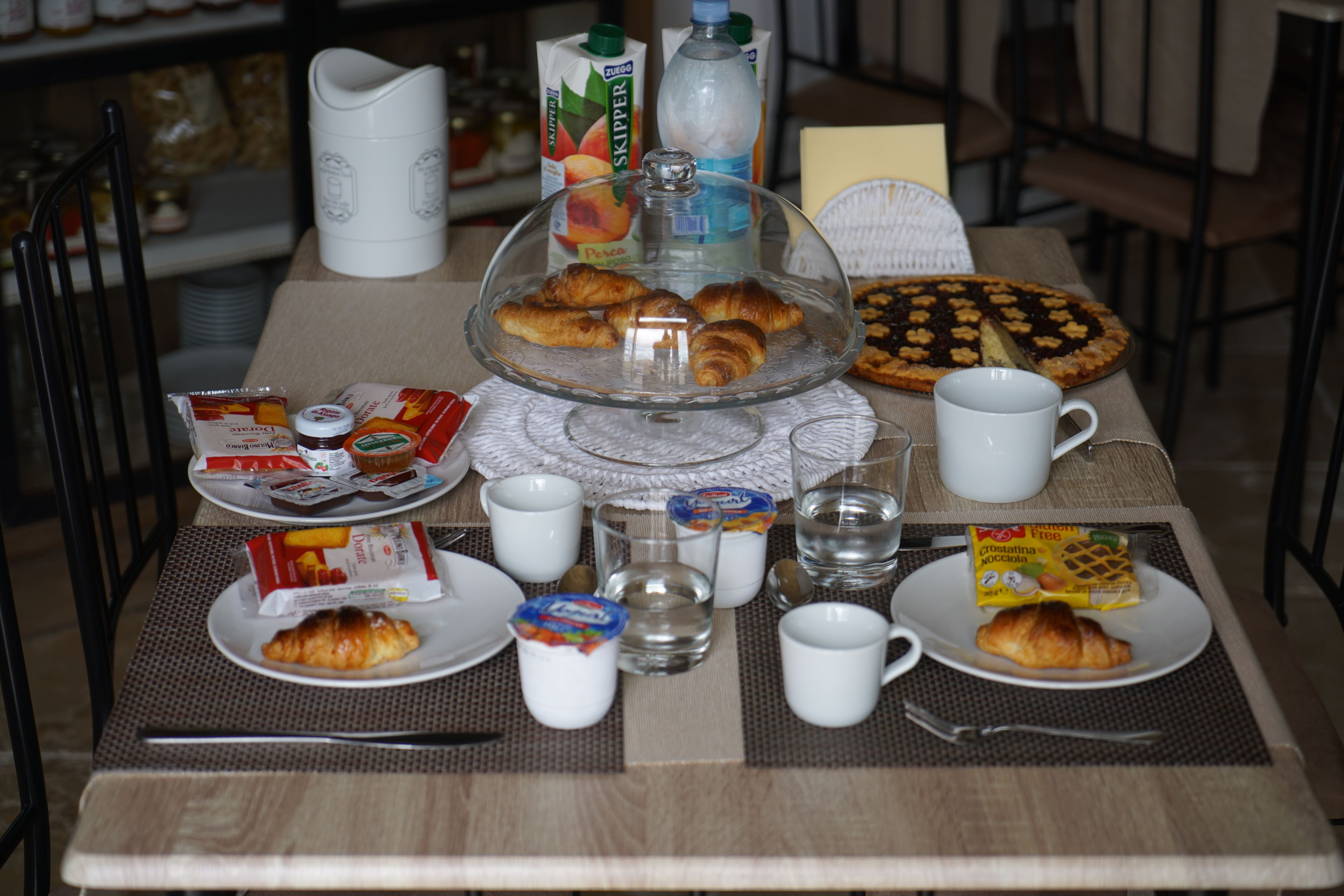 Ein Frühstückstisch mit Croissants, einem Kuchen und verschiedenen Frühstücksleckereien.