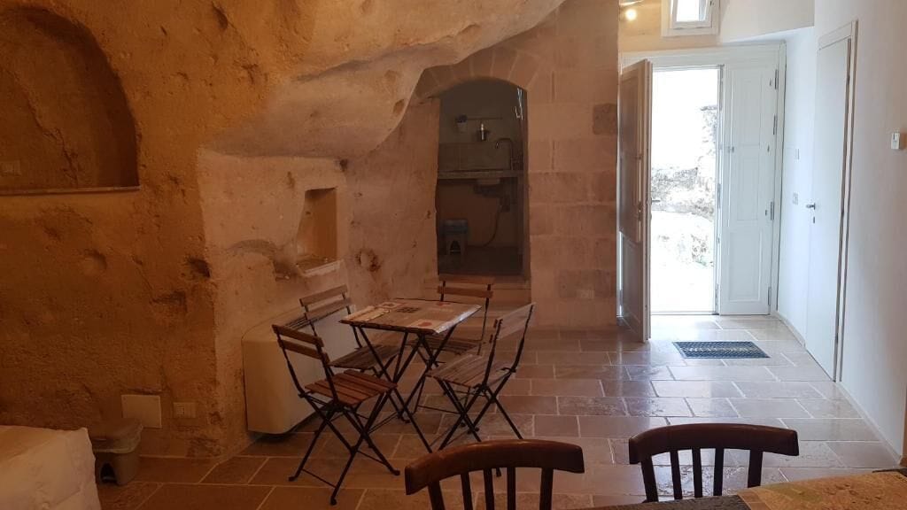 A dining area with a table and chairs, a stone wall, and a door leading outside.