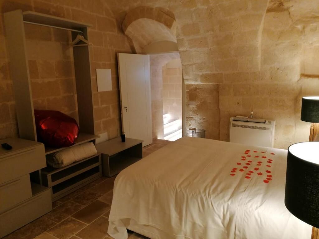 A bedroom with a bed, a wardrobe, a mirror, a heater, and a lamp.