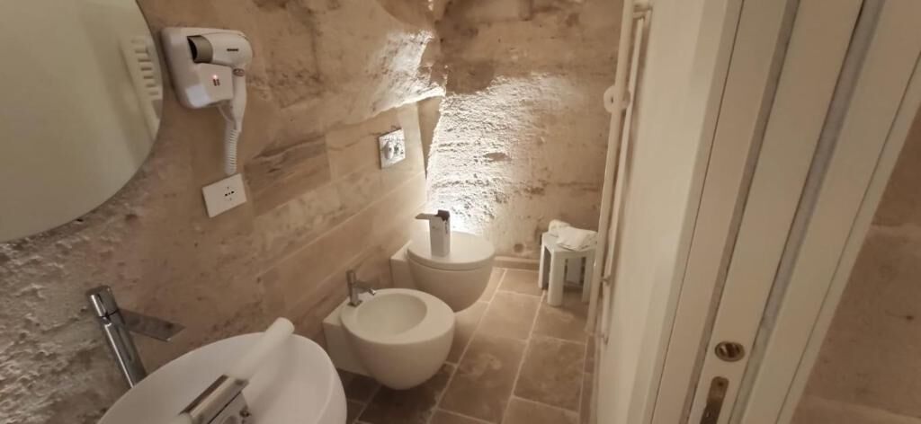 Un baño pequeño con inodoro, lavabo y un secador de pelo en la pared.