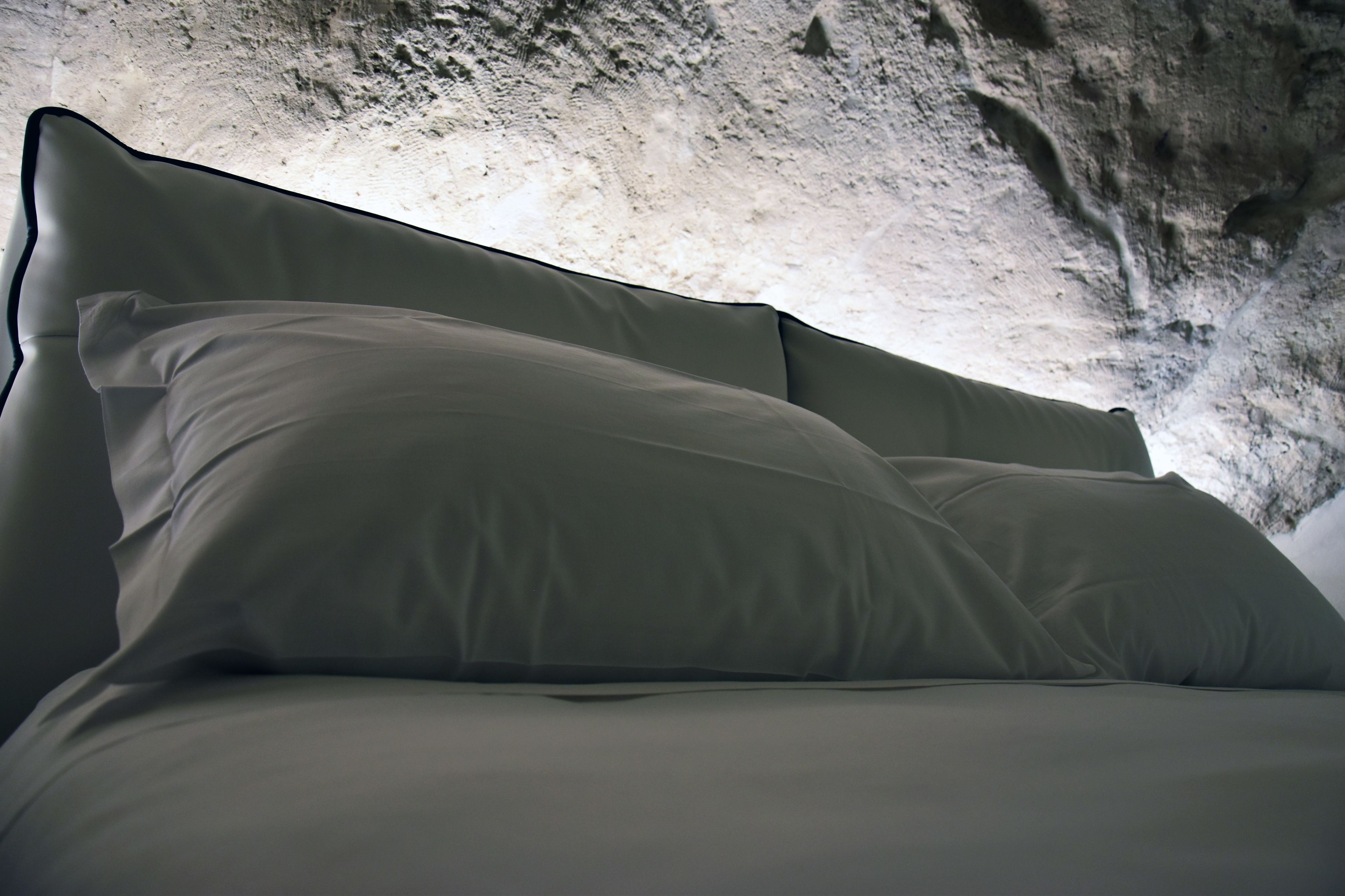 Una cama con cabecera frente a una pared con textura.