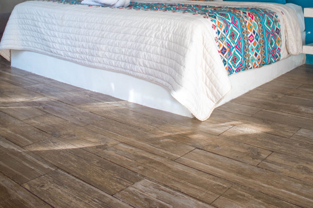 A bedroom with a bed, ceiling fan, air conditioning unit, and a decorative wall piece.