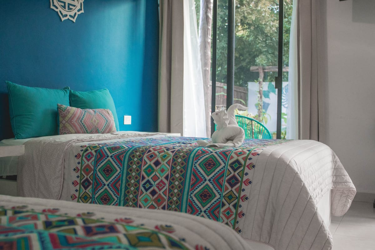 A bedroom with a bed, a window, and a view of greenery outside.