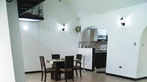 A spacious living area with a dining table and chairs, a kitchen in the background, and a unique black and white floor design. - Casa Grande Exclusiva Zona Norte (Armenia)