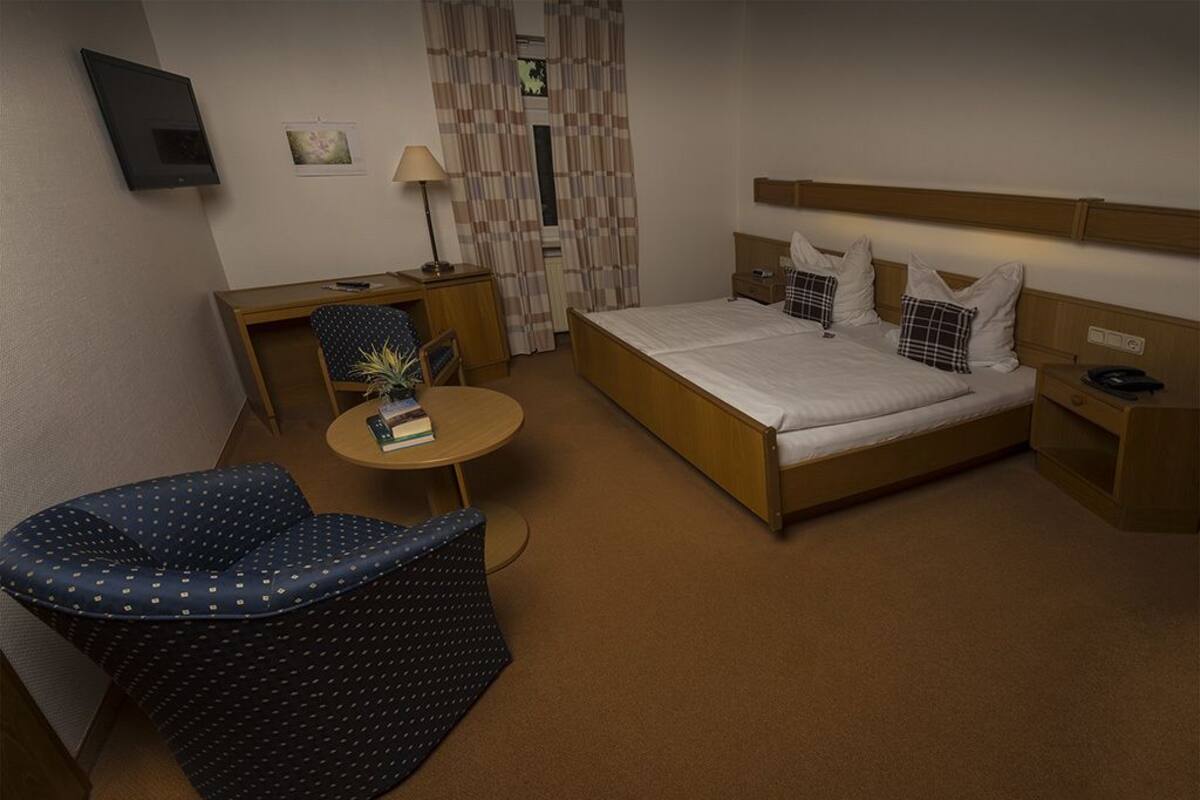 Une chambre d’hôtel équipée d’un lit, d’un bureau, d’une chaise, d’une petite table et d’un téléviseur.