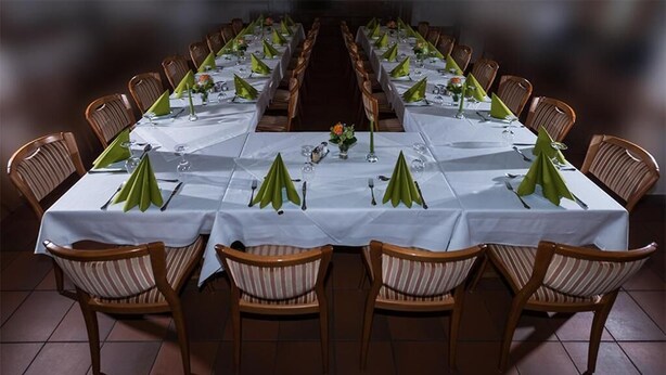 A long dining table set for a formal meal with chairs, centerpieces, and table settings.