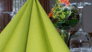 A table set with a green tablecloth, a vase of flowers, and a wine glass.
