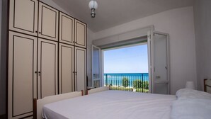 Una camera da letto con un letto, un armadio e un balcone vista mare.