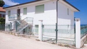 Un edificio a due piani con un balcone, una scala e un'area recintata.
