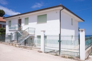 A two-story building with a balcony, a staircase, and a fenced area.