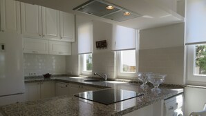 A modern kitchen with white cabinets, granite countertops, a stainless steel sink, and a built-in dishwasher. - Villa White (Datça)