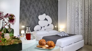 Un dormitorio moderno con una cama, mesitas de noche, un diseño decorativo en la pared y vistas al exterior.