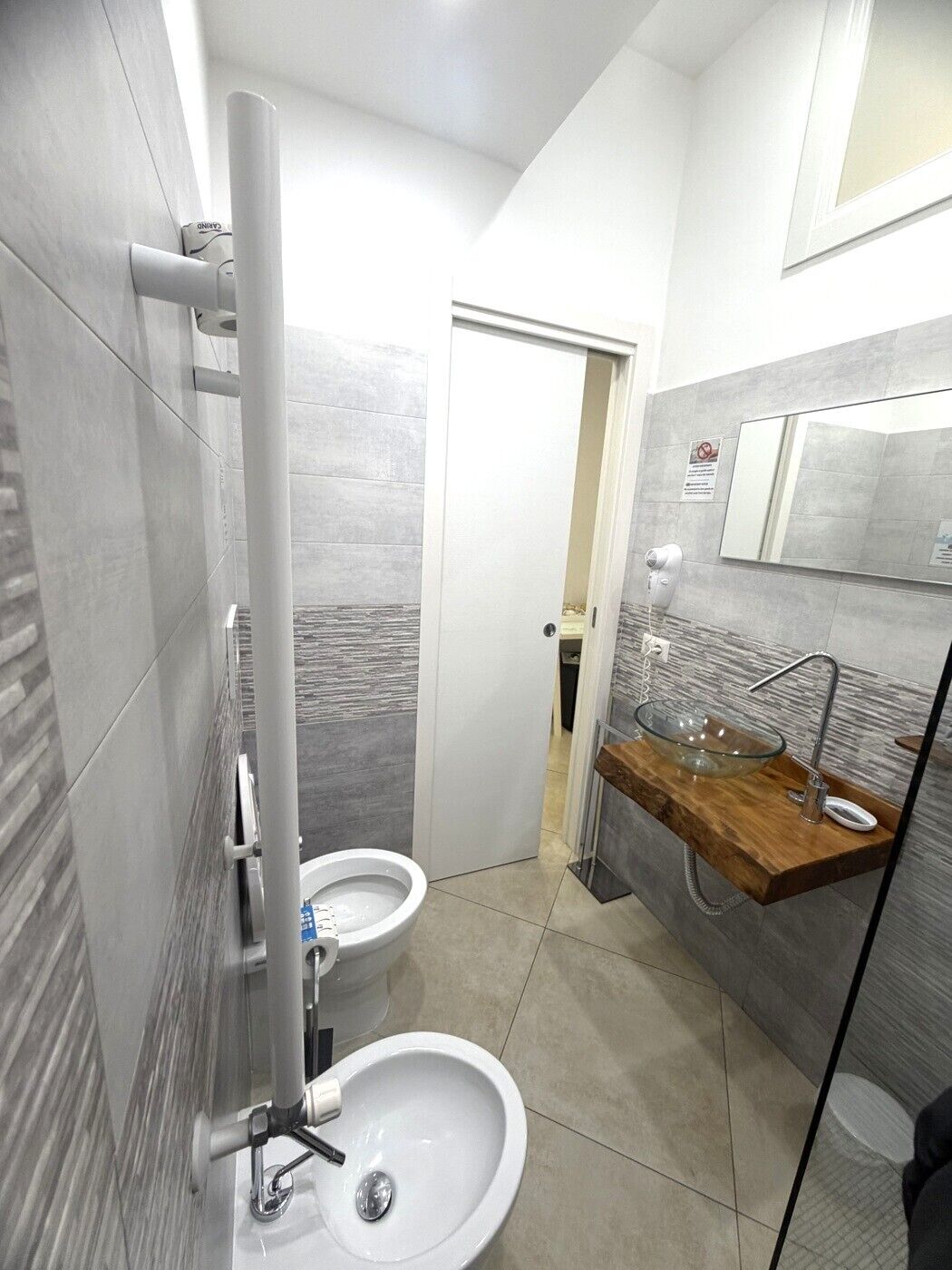 A modern bathroom with a glass bowl sink, a toilet, and a bidet.