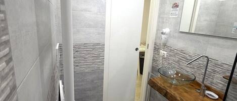 A modern bathroom with a glass bowl sink, a toilet, and a bidet.