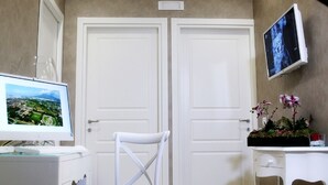 Una habitación con escritorio, silla, computadora, televisor y una puerta.