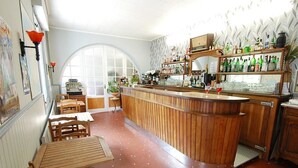 Uma área de bar com móveis de madeira, um balcão curvo e prateleiras com garrafas.
