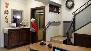 Uma área de recepção de hotel com uma mesa de madeira, um relógio e uma escadaria.