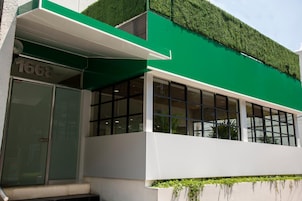Un edificio moderno con facciata verde, ampie finestre e il numero 1668 ben visibile.