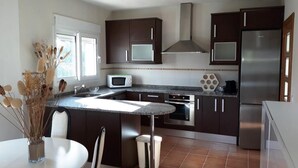 Una cocina moderna con gabinetes oscuros, electrodomésticos de acero inoxidable y una isla central.