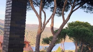 Vista de un edificio con una chimenea de ladrillo, rodeado de árboles y una masa de agua al fondo.
